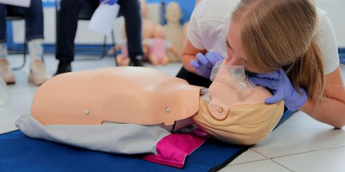 woman-practicing-cpr-on-mannequin-at-first-aid-class